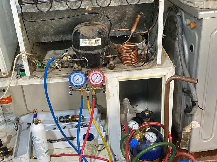 Heladera en reparación en el taller, con manómetros conectados al compresor