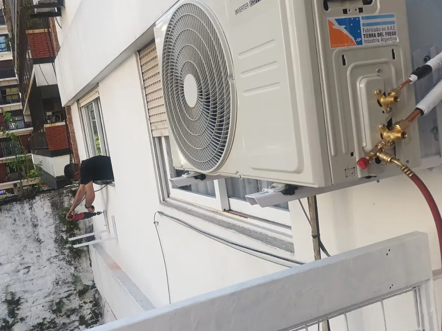 Técnico de RECTEC instalando la unidad exterior de un aire acondicionado en un balcón de Boedo